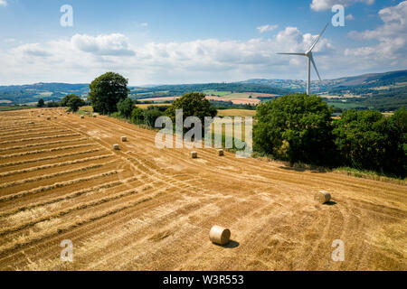 Vista aerea di balle di paglia con una turbina eolica su terreni agricoli in Wales UK Foto Stock