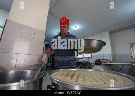 Luglio 17, 2019 - Gaza City, nella Striscia di Gaza, Territori palestinesi - un lavoratore palestinese si prepara dolci davanti ai risultati di alta scuola esami, noto come ''Tawjihi'', in occasione di un seminario di Gaza City, 17 luglio 2019 (credito Immagine: © Mahmoud Ajjour/APA immagini via ZUMA filo) Foto Stock