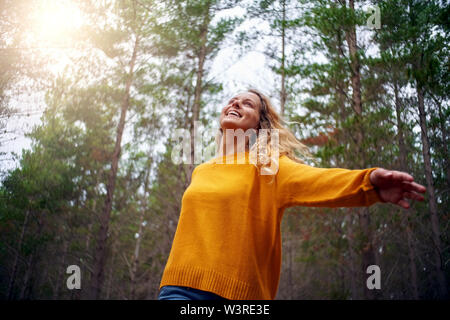 Felice bella ragazza bionda dancing in foresta Foto Stock