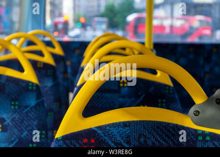 All'interno di un autobus a due piani posti vuoti. Interno con giallo e blu di sedie e sedili. Foto Stock