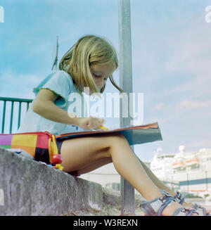 Ragazza giovane disegno nel libro al di fuori Foto Stock