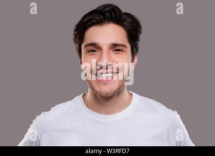 Bel giovane uomo caucasico sorridente in telecamera Foto Stock