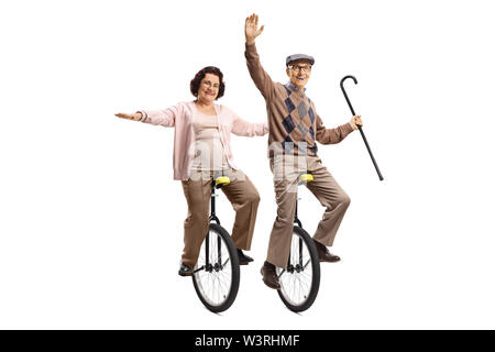 A piena lunghezza shot di un uomo anziano tenendo un bastone da passeggio e una donna anziana unicycles equitazione e sorridente isolati su sfondo bianco Foto Stock