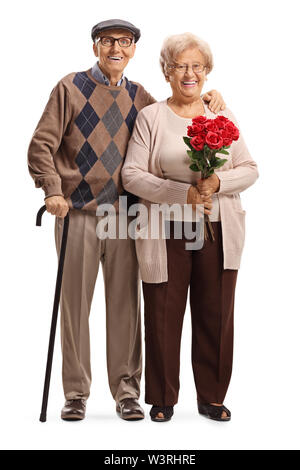 A piena lunghezza Ritratto di una coppia senior in piedi con rose rosse isolato su sfondo bianco Foto Stock