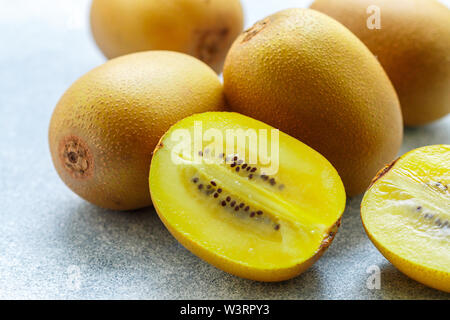 Golden (giallo) organica kiwi. Tutto il taglio e maturi frutti succosi su sfondo grigio. i kiwi. Actinidia chinensis. Messa a fuoco selettiva Foto Stock