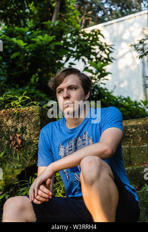 Un bel ragazzo seduto sulla scala nel parco Foto Stock