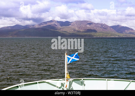 Vista dell'isola di Arran mostra Goatfell montagna, Firth of Clyde, dalla prua del Caledonian MacBrayne traghetti battenti lo scozzese si intraversa bandiera, Foto Stock