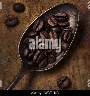 Primo piano di un cucchiaio colmo di tostatura del caffè in grani Foto Stock