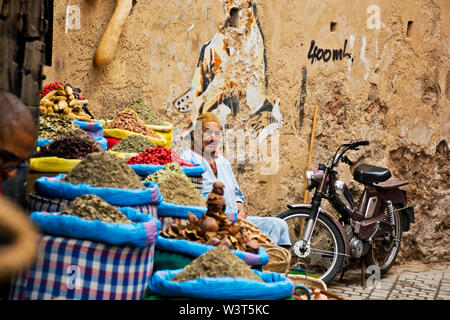 Locale marocchino uomo vendita di merci nelle strade e vicoli di Marrakech andando su quotidiana vita araba in weathered Medina culturale Foto Stock