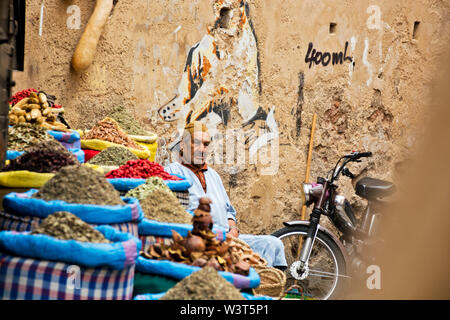 Locale marocchino uomo vendita di merci nelle strade e vicoli di Marrakech andando su quotidiana vita araba in weathered Medina culturale Foto Stock