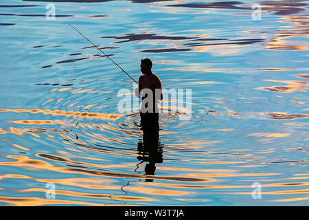 Silhouette di un pescatore in riflessione astratta di ondulazioni di acqua Foto Stock