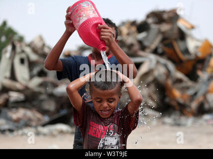 La striscia di Gaza. 17 Luglio, 2019. Un bambino palestinese è versata con acqua per rimanere fresco durante la stagione calda, nel sud della striscia di Gaza city di Khan Younis, 17 luglio 2019. Credito: Yasser Qudih/Xinhua/Alamy Live News Foto Stock