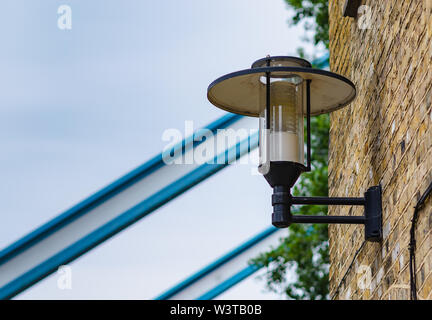 Round Lanterna di metallo su un muro di mattoni, da qualche parte a Londra, Regno Unito, vicino al Tower Bridge. Foto Stock