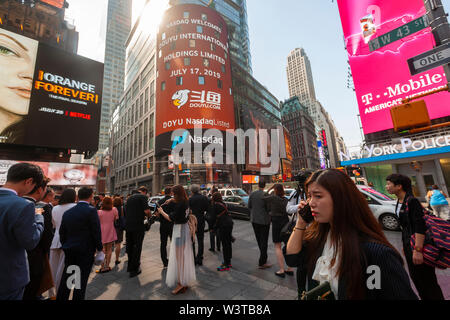 I dipendenti con le loro famiglie e i loro amici a raccogliere il gigantesco schermo video sul Nasdaq stock exchange in Times Square a New York decorato per il debutto della DouYu International Holdings Ltd. offerta pubblica iniziale su Mercoledì, 17 luglio 2019. DouYu è il più grande live-streaming platform in Cina ed è sostenuta da Tencent Holdings Ltd. La valutazione della società a $3,73 miliardi di euro è la più grande IPO cinese nel 2019. (© Richard B. Levine) Foto Stock