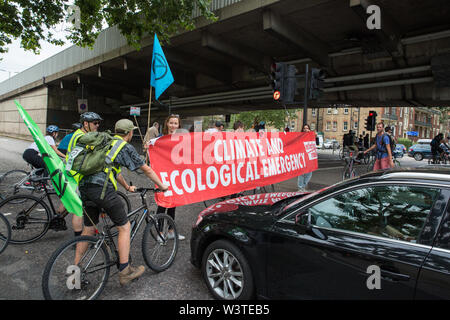 Londra, Regno Unito. 17 Luglio, 2019. Gli attivisti del clima dalla ribellione di estinzione bloccare la strada per attivare una massa critica di bicicletta da Waterloo Millennium verde a Hammersmith Town Hall a passare. Attivisti per la corsa al terzo giorno della loro 'Summer uprising' hanno tre richieste per Hammersmith e Fulham consiglio: per far passare la proposta di dichiarare una emergenza climatica; per mantenere Hammersmith Bridge chiusa per veicoli; e impegnarsi a safer itinerari in bicicletta. Credito: Mark Kerrison/Alamy Live News Foto Stock