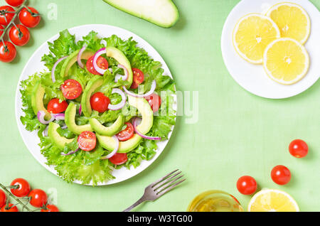 Cibo vegetariano. Con insalata di avocado, cipolla rossa e pomodori sulla piastra bianca. Vista superiore, laici piatta Foto Stock