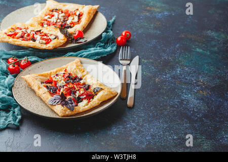 Pasta sfoglia canapes con pomodori, dolci peperoni, salame, formaggio feta e basilico viola. Foto Stock