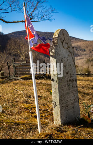 Bandiera confederata strappata accanto a una lapide in un cimitero in cima a una collina vicino Bakersville, Mitchell County, North Carolina, USA. Foto Stock