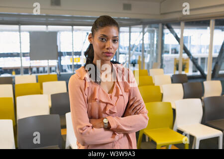 Imprenditrice in piedi con le braccia incrociate in un ufficio moderno Foto Stock