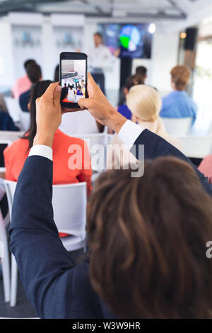Close-up di imprenditore facendo clic su foto del seminario di business con il telefono cellulare Foto Stock