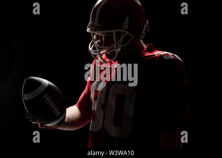 Giocatore di football americano con helmat guardando il pallone da rugby Foto Stock