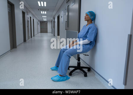Teso chirurgo femmina seduto su uno sgabello in corridoio Foto Stock