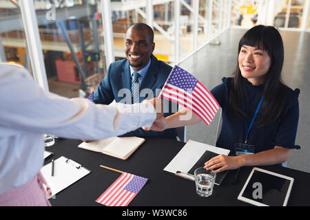 La gente di affari tenendo una bandiera americana durante la conferenza per la tabella di registrazione Foto Stock