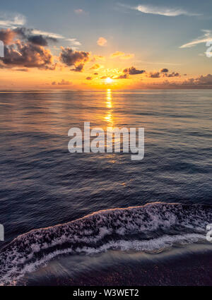 Bellissimo tramonto dei Caraibi con spruzzi di acqua in primo piano e arancio e blu cielo in background Foto Stock