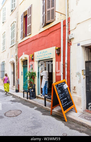 Marseille, Francia - 8 Settembre 2015: una donna cammina davanti a un piccolo ristorante,. La vecchia area portuale ha molti vecchi edifici. Foto Stock