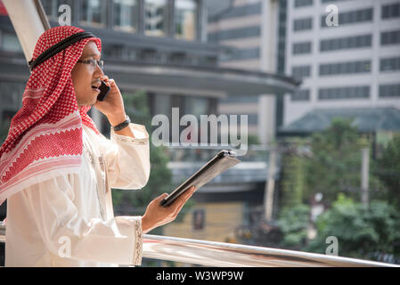 Smart bello imprenditore araba utilizzando il telefono cellulare nella città. Foto Stock