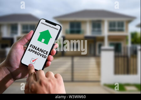 Finanziare l'accordo di prestito e la chiave di casa mutuo ipotecario approvazione sul telefono cellulare in una casa Foto Stock