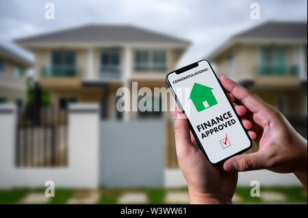 Finanziare l'accordo di prestito e la chiave di casa mutuo ipotecario approvazione sul telefono cellulare in una casa Foto Stock