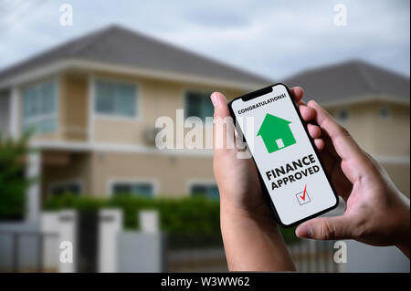 Finanziare l'accordo di prestito e la chiave di casa mutuo ipotecario approvazione sul telefono cellulare in una casa Foto Stock