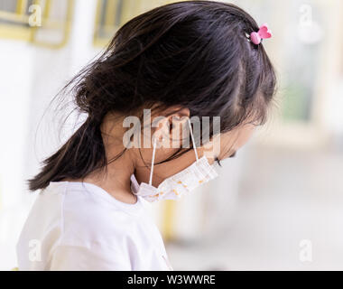 Bambina sta mettendo la sua maschera su per evitare l'inquinamento atmosferico