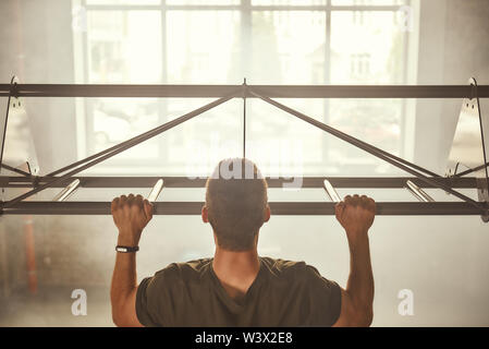 Just do it vista posteriore di un uomo forte facendo pull-up mentre ti alleni in palestra. Sport concept. Bodybuilding Foto Stock