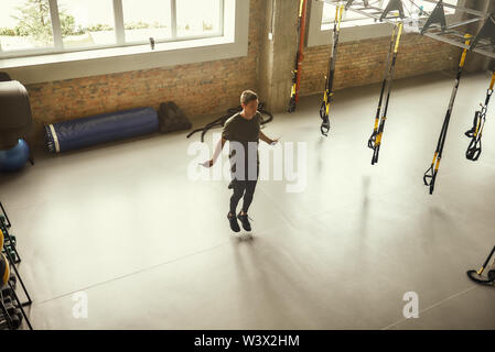 Per tutta la lunghezza della giovane uomo sportivo è corda da salto mentre ti alleni in palestra. Sport concept. Fitness. Vita attiva Foto Stock