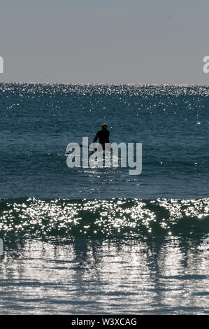 Una giovane donna rema fuori in mare di corallo nel suo kayak per un'esercizio del mattino da Agnes Water Beach a Agnes Water nel Queensland, Australi Foto Stock