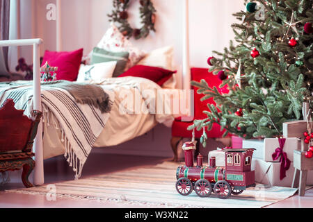 Per l'anno nuovo locomotore giocattolo sotto l'albero in camera da letto Foto Stock