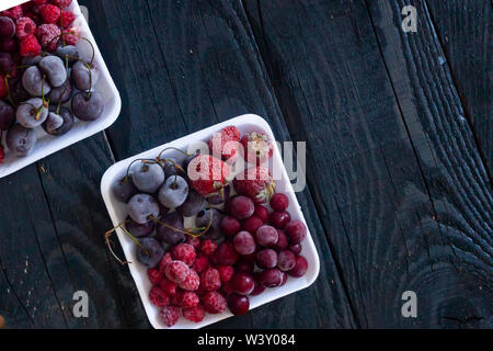 Una sana dolce con su scuri in legno rustico sfondo. Frutta congelata. Spazio di copia Foto Stock