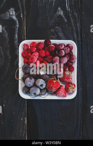 Una sana dolce con su scuri in legno rustico sfondo. Frutta congelata. Spazio di copia Foto Stock