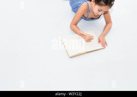 Vista superiore della felicità ragazza disegno nel disegno libro sul pavimento bianco a casa o asilo nido. Lo stile di vita delle persone e bambini a giocare. L'istruzione e i bambini del concetto. B Foto Stock