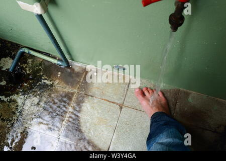 Movimento sfocate di acqua che scorre sul piede destro dita dei piedi di un uomo asiatico Foto Stock