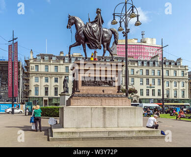 Statua della regina Victoria in George Square e centro della città di Glasgow Scotland Regno Unito con il Millennium Hotel dietro Foto Stock