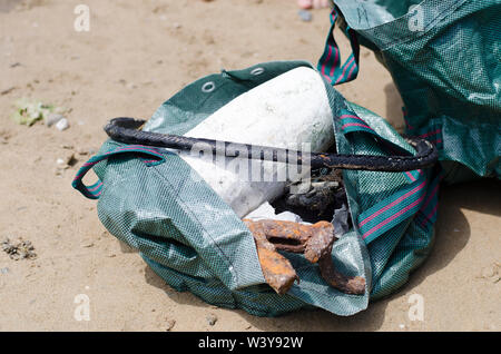 Cestino raccolti in robusto sacchetto durante la spiaggia pulita Foto Stock