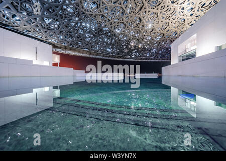 Louvre, Abu Dhabi, Emirati Arabi Uniti - Dic29, 2017: bianco corpss della galleria, in piedi in acqua di mare sotto un openwork luminosa cupola Foto Stock