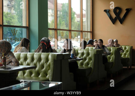 Giovani donne seduti in un caffè ristorante all'interno di un centro commerciale a Grozny la capitale della Cecenia ufficialmente la Repubblica cecena nel Nord Caucaso Distretto federale della Russia. Foto Stock