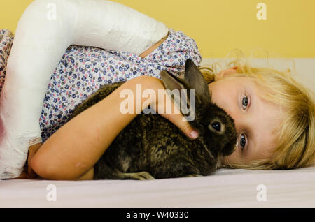 Ragazza caucasica con spalla rotta e animale di coniglio Foto Stock