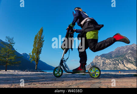 Scooter passa a nord sulla spiaggia di sunrise al piccolo porto Porticcioloat Lago di Garda, il Lago di Garda in Torbole - Nago, Riva, Trentino , Italia a aprile Foto Stock