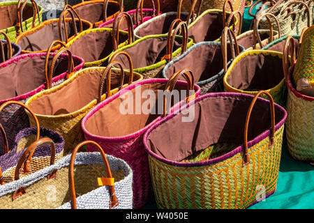 Un display di colorate a mano cestini di vimini per la vendita in un mercato francese adatto per il trasporto di shopping Foto Stock