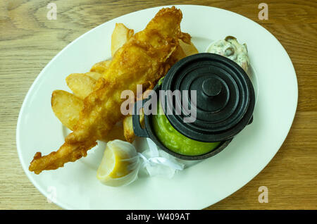 Fish & Chips con una pentola di fiacco di piselli e di un cuneo di limone Foto Stock